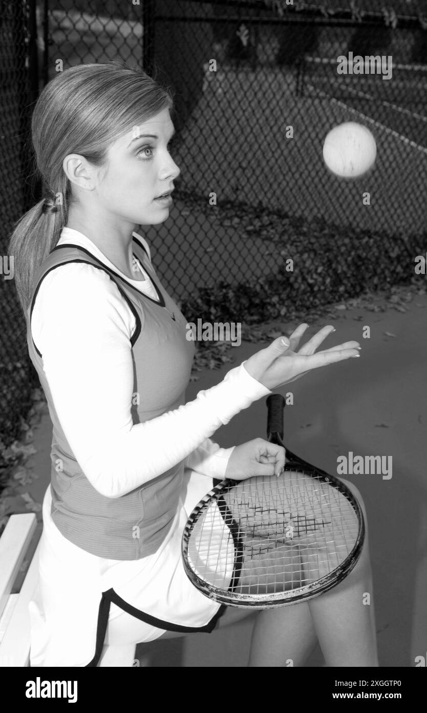 Adolescente caucasica che lancia una palla da tennis in aria tenendo una racchetta. Foto Stock