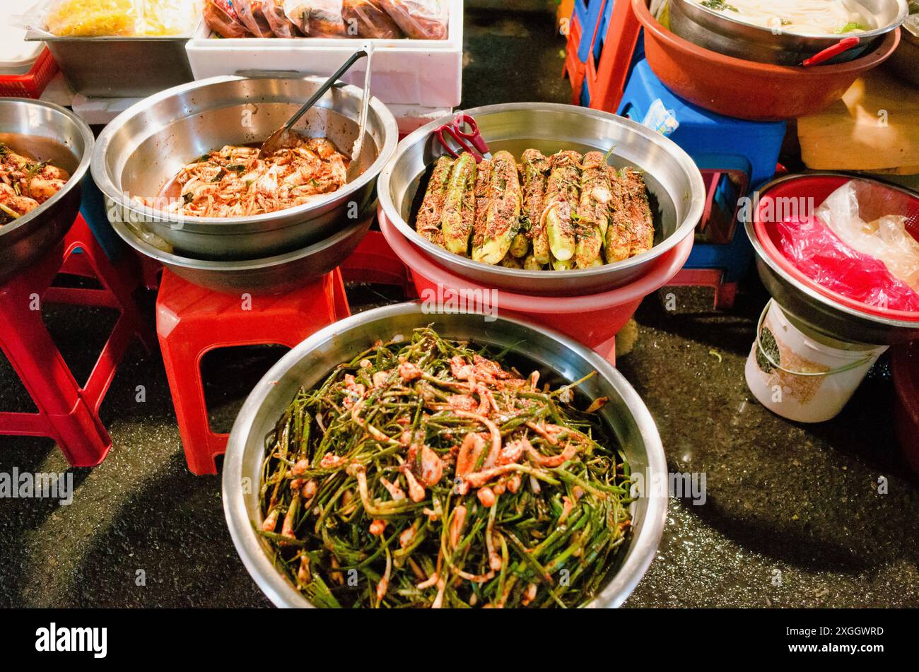 Varietà di Street food coreano esposto in ciotole di metallo, con piatti colorati e piccanti Foto Stock