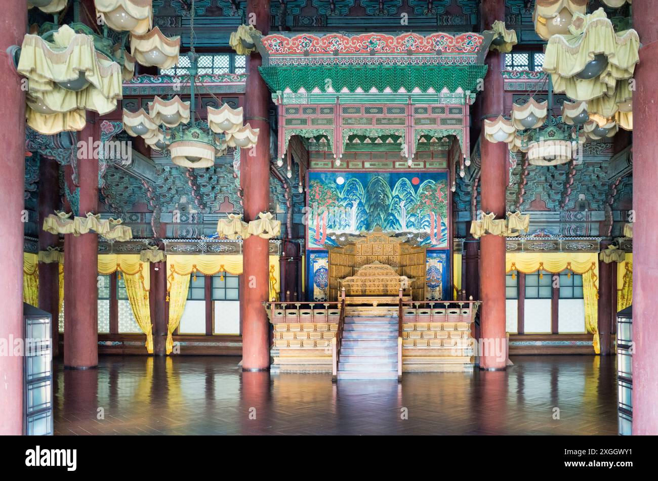 Sala del trono del palazzo coreano decorata con intricate decorazioni, trono dorato e vibrante murale Foto Stock