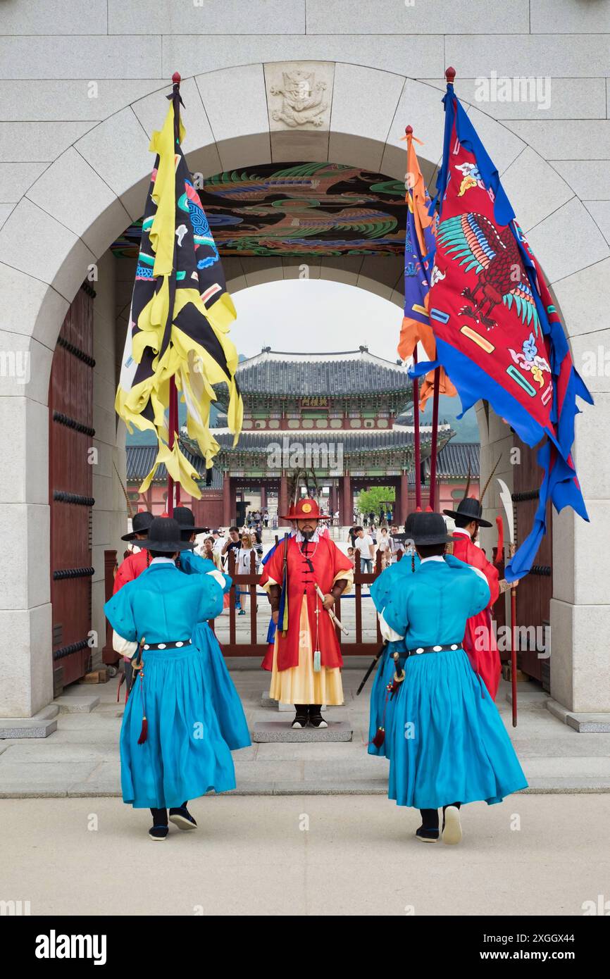 Guardie colorate in tradizionale abbigliamento reale coreano si trovano all'ingresso del palazzo, mescolando storia e turismo moderno Foto Stock