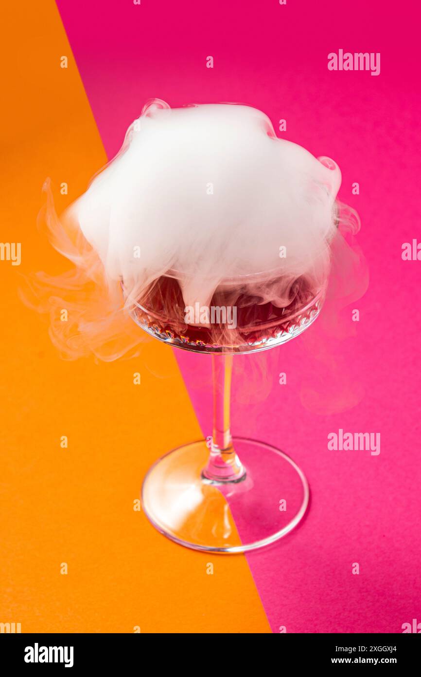 Bevi con fumo su un vivace sfondo rosa-arancione. Bevanda esplosiva. Bevanda esotica. Foto Stock