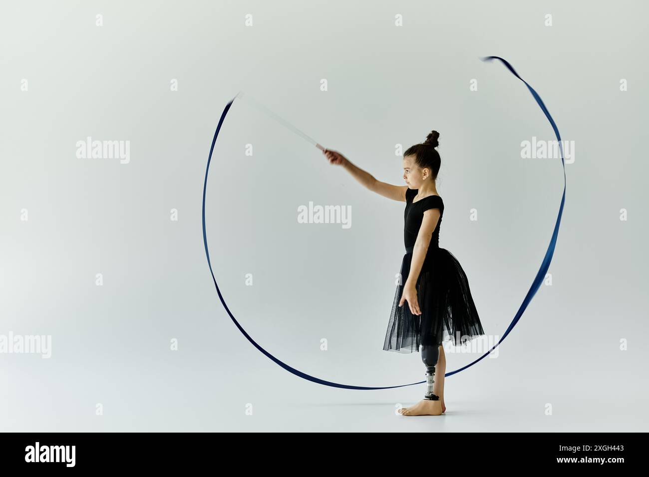 Una giovane ragazza con una gamba protesica esegue una graziosa routine di danza del nastro. Foto Stock