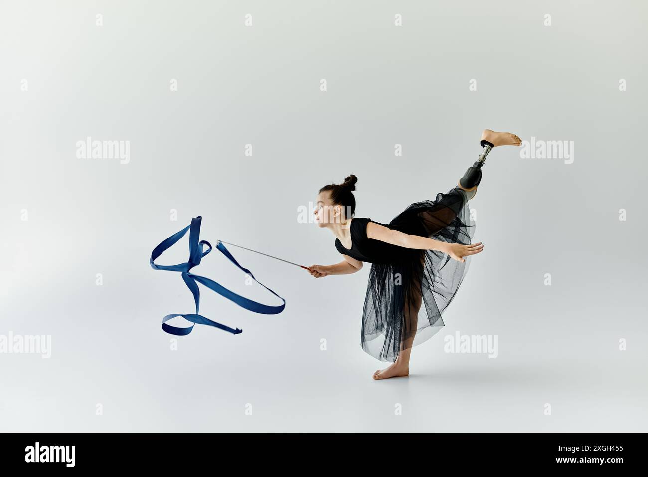 Una giovane ragazza con una gamba protesica esegue una graziosa routine di ginnastica con un nastro. Foto Stock