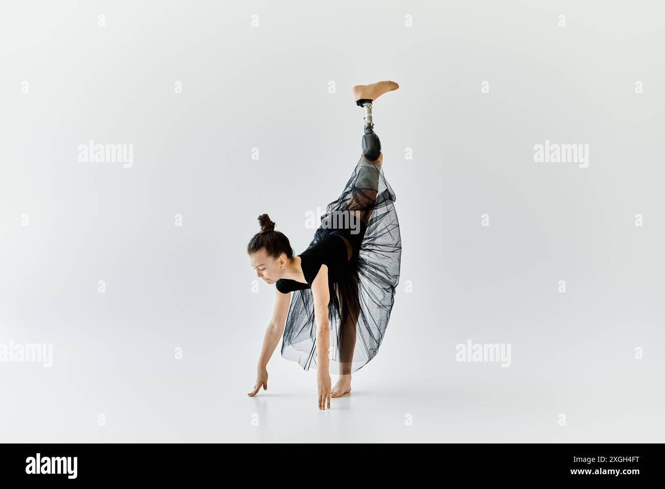 Una giovane ragazza con una gamba protesica esegue una graziosa posa ginnastica. Foto Stock