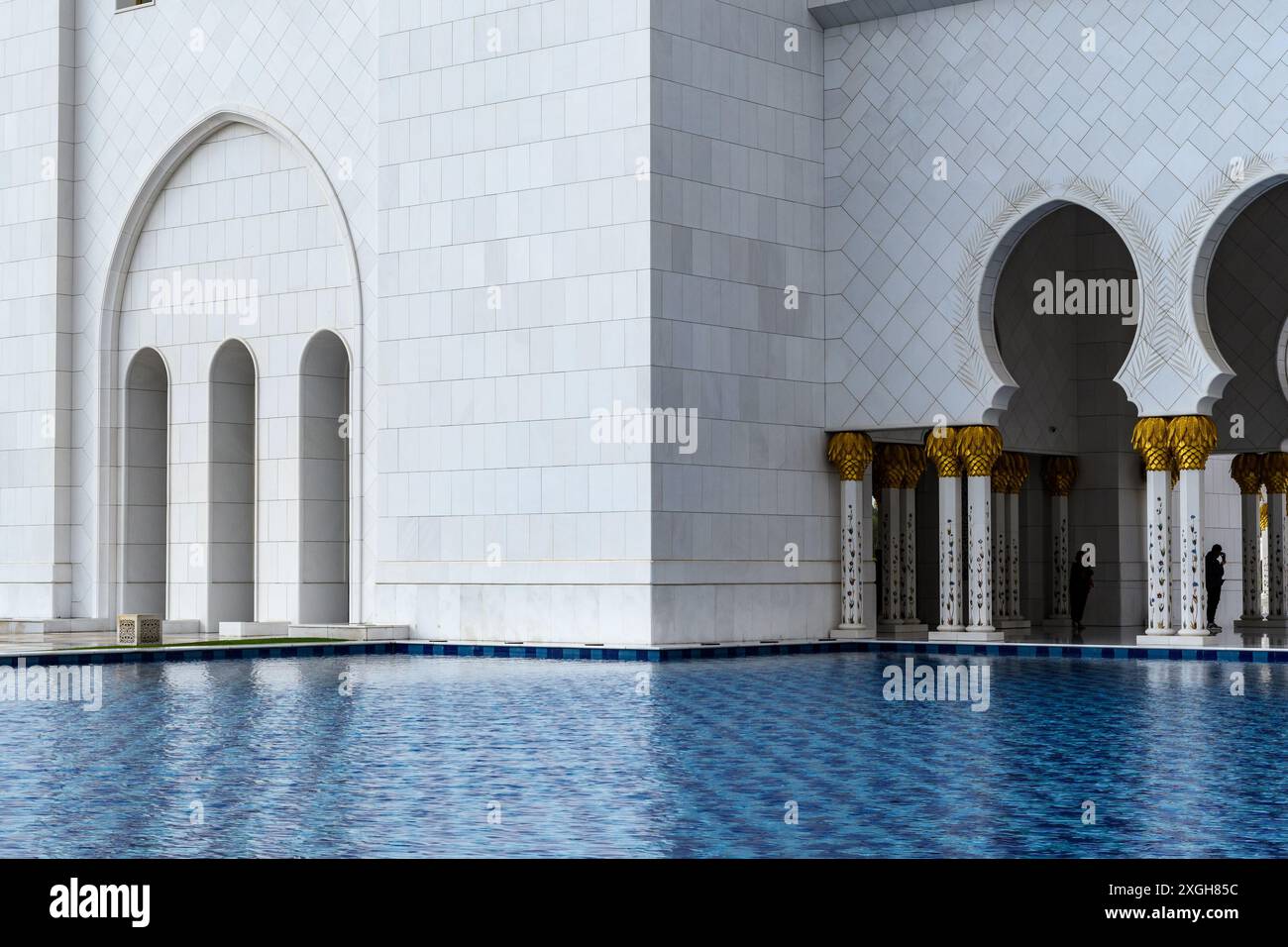 Abu Dhabi, Emirati Arabi Uniti - 4 gennaio 2024: Eleganti archi e acque riflettenti presso la grande Moschea dello sceicco Zayed di Abu Dhabi. Foto Stock
