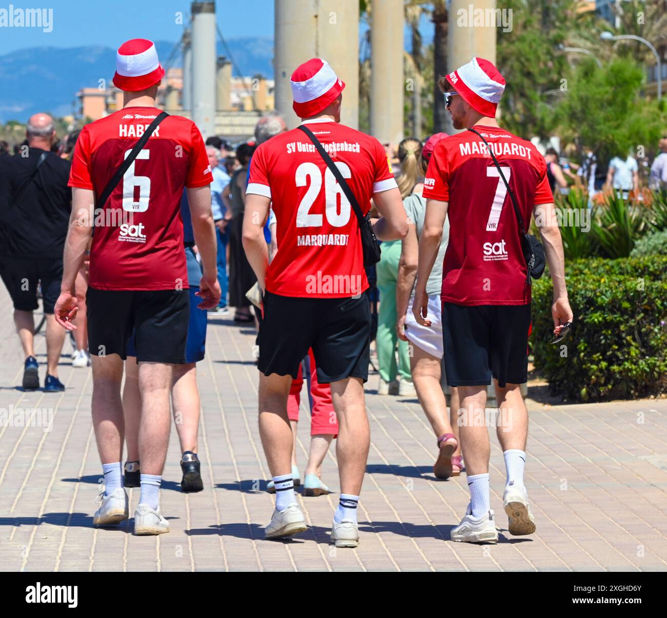 Un gruppo di giovani vacanzieri maschi con magliette da calcio rosse cammina lungo la passeggiata di El Arenal, Playa de Palma, Maiorca, Spagna Foto Stock