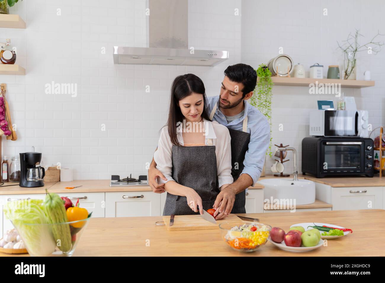 In cucina, una coppia felice prepara perfettamente cibo sano, un sacco di verdure, un ragazzo giocherà con la frutta, facendo ridere il suo ragazzo. Ragazzi carini io Foto Stock