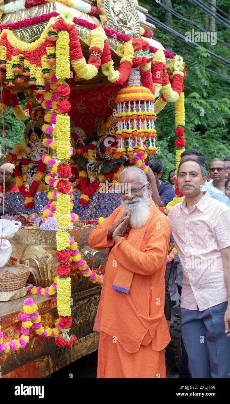 Il sacerdote indù Rameshum posa di fronte al carro usato nel Ratha Yatra del 2024 a Wilton, Connecticut. Sono a metà del viaggio qui. Foto Stock