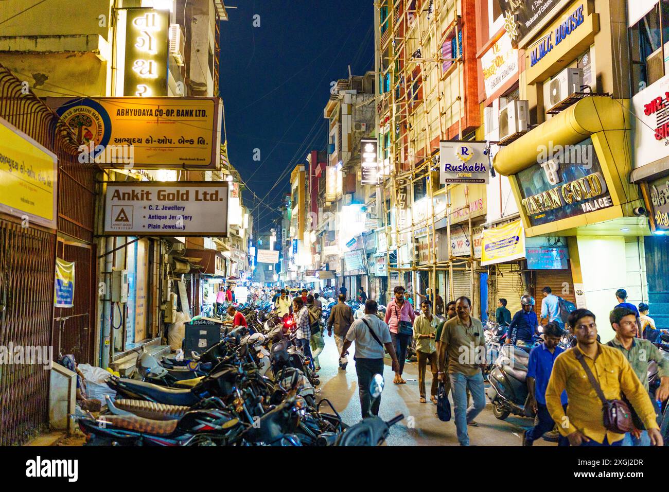 Ahmenabad, India - 13 ottobre 2023: Le persone si vedono camminare di notte nel centro della città tra gioiellerie e negozi d'oro. Affollata e trafficata strada indiana Foto Stock