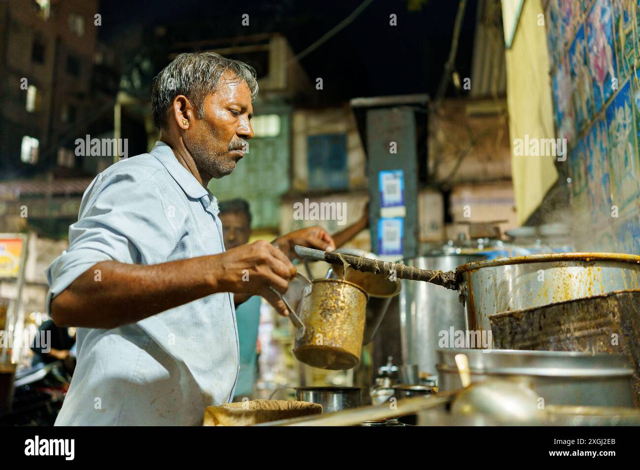 Ahmenabad, India - 20 ottobre 2023: Un venditore di chai di strada viene visto vendere chai di notte. Vecchio indiano che fa un lavoro informale, concetto di sostentamento in Foto Stock