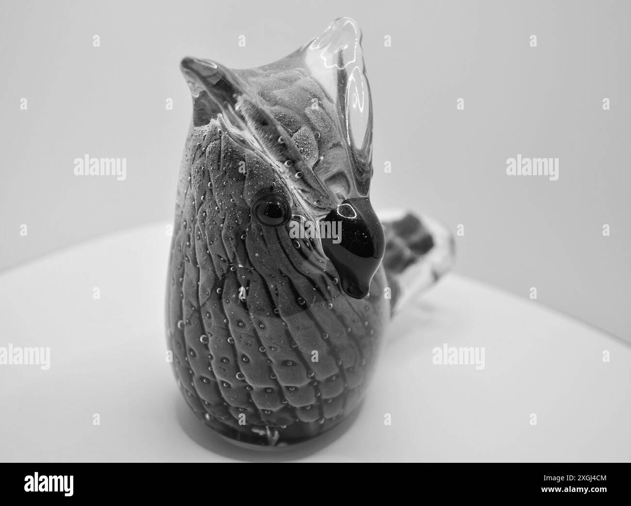 Figurina di Gufo di vetro bianco e nero su Una superficie bianca Foto Stock