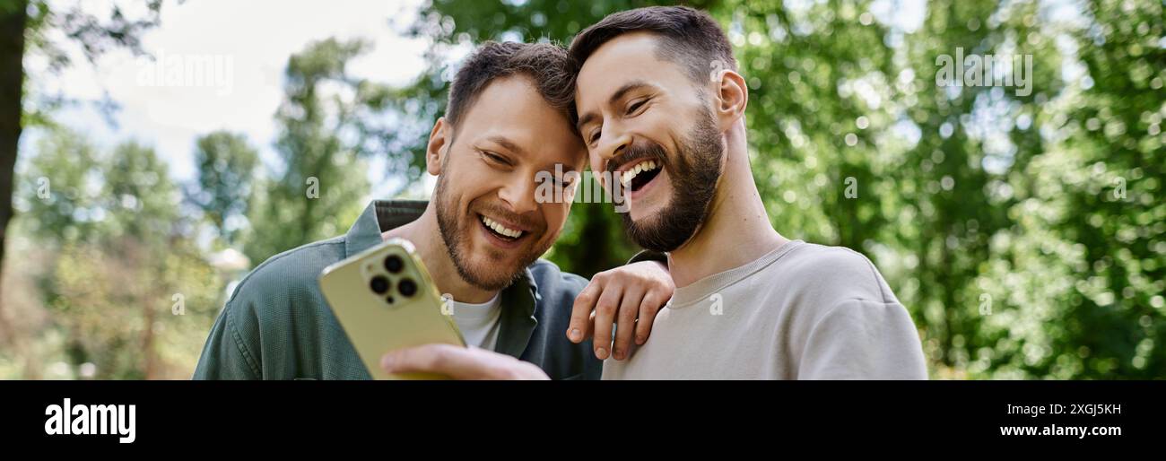 Due uomini gay barbuti stanno ridendo insieme in un parco. Foto Stock