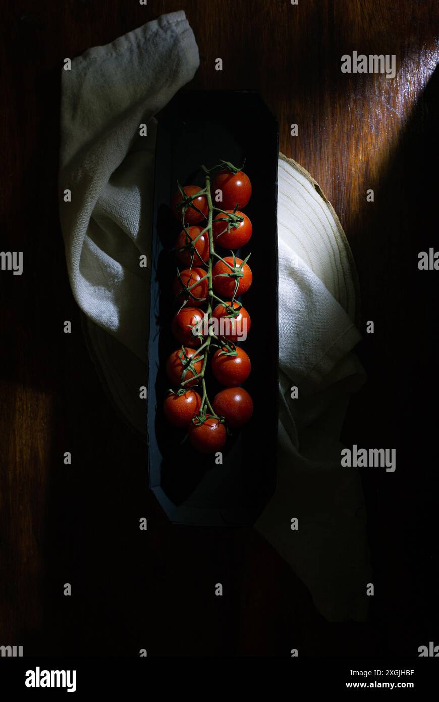Natura morta di basso livello. Primo piano di un vassoio di pomodori. Il vassoio si trova su un tavolo di legno e i pomodori sono disposti in fila. L'immagine ha un caldo Foto Stock
