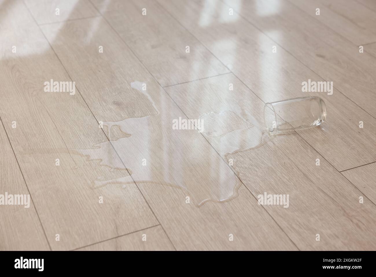 Bicchiere con bibita versata su pavimento in legno Foto Stock