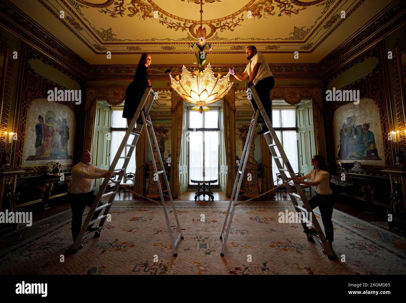 I preparativi finali sono fatti nella Centre Room, dove i membri del personale della Royal Collection Trust tendono ad un lampadario, nell'ala est di Buckingham Palace, Londra, aperto ai visitatori per la prima volta quest'estate, quando speciali visite guidate del piano principale saranno disponibili per i visitatori a luglio e agosto. Data foto: Lunedì 8 luglio 2024. Foto Stock