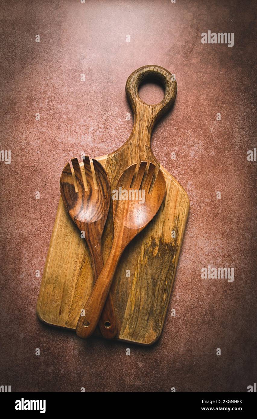 Cucchiaio di legno, con chiodi di garofano, per insalata, due pezzi, legno naturale, con tagliere, sfondo alimentare, sfondo, vista dall'alto Foto Stock