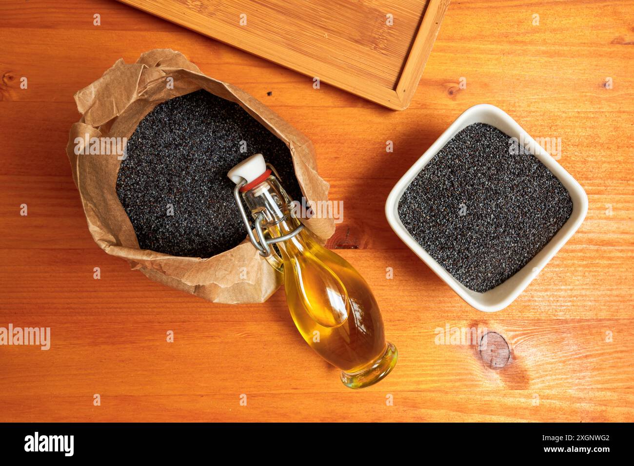 Olio di semi di papavero commestibile o olio di semi di papavero con alcuni semi di papavero di oppio secchi sul tavolo da cucina, attenzione selettiva Foto Stock