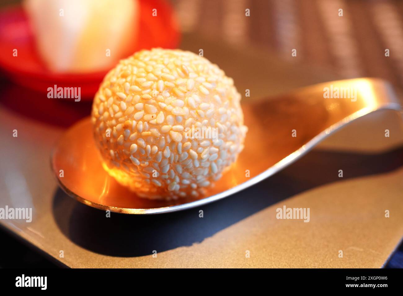 Palla di semi di sesamo appena fritta su un cucchiaio dorato Foto Stock