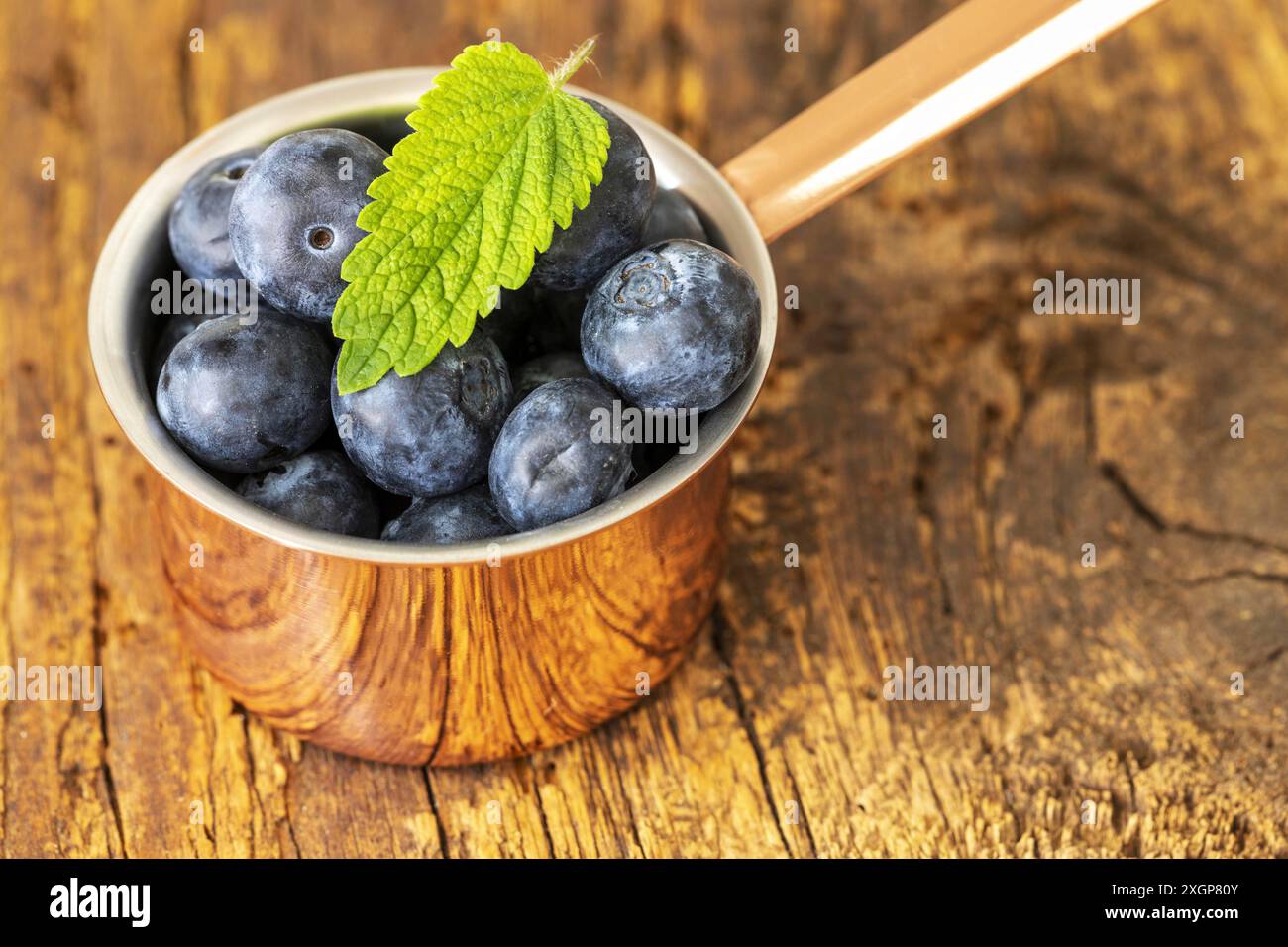 Bacche blu in una pentola su legno Foto Stock
