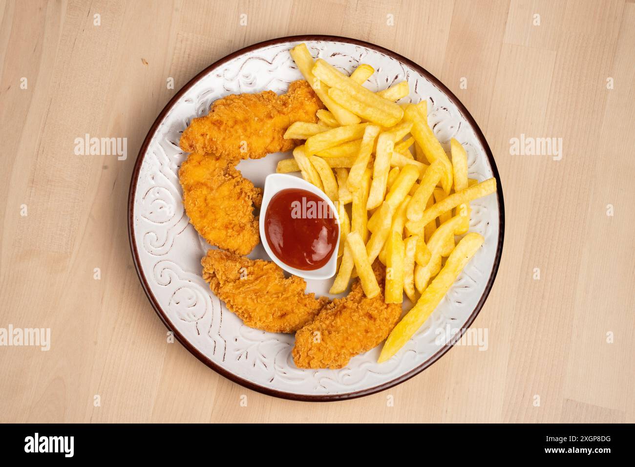 Un piatto di ali di pollo fritte croccanti con patatine fritte e un lato di ketchup su un tavolo di legno Foto Stock