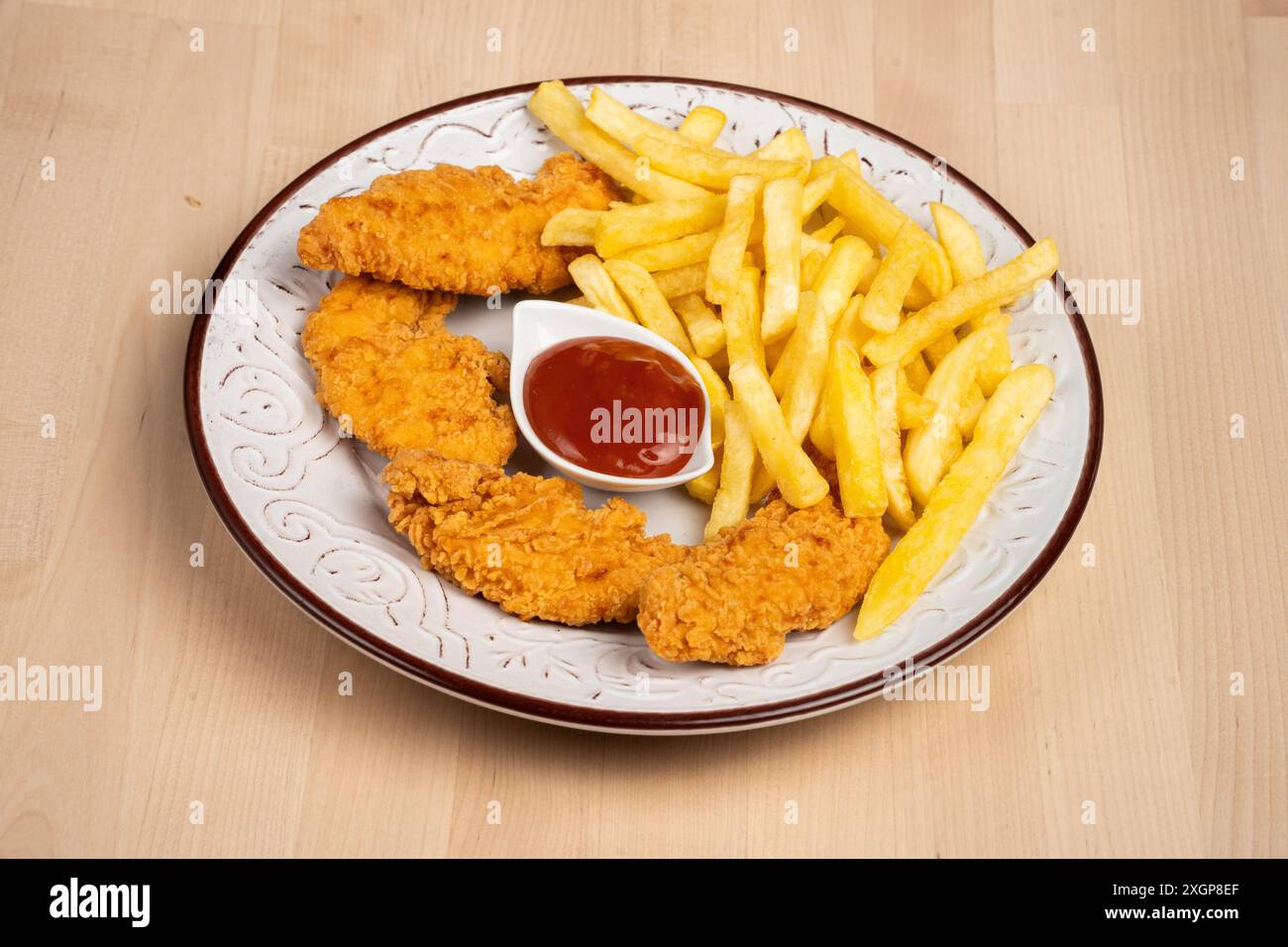 Un piatto di ali di pollo fritte croccanti con patatine fritte e un lato di ketchup su un tavolo di legno Foto Stock