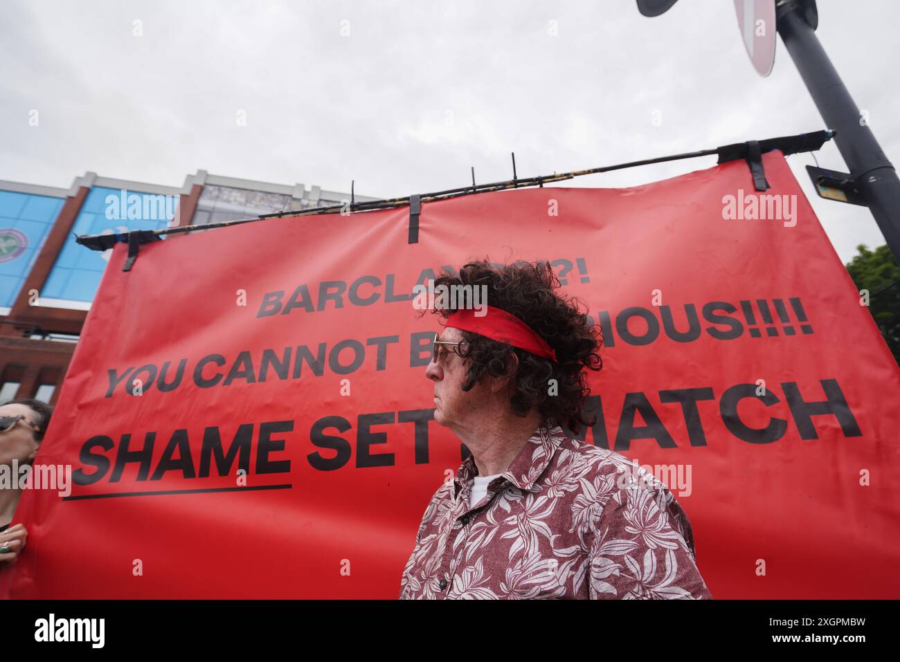 Londra, Regno Unito. 10 luglio 2024 . Un manifestante come John McEnroe si presenta davanti a uno striscione che recita "Shame Set and Match" per protestare contro l'All England Lawn Tennis Club usando Barclays come sponsor del Wimbledon Championships che sta finanziando la distruzione di antiche foreste, alimentando il crollo climatico, e società di finanziamento che forniscono armi legate a Israele Credit: Amer Ghazzal/Alamy Live News Foto Stock