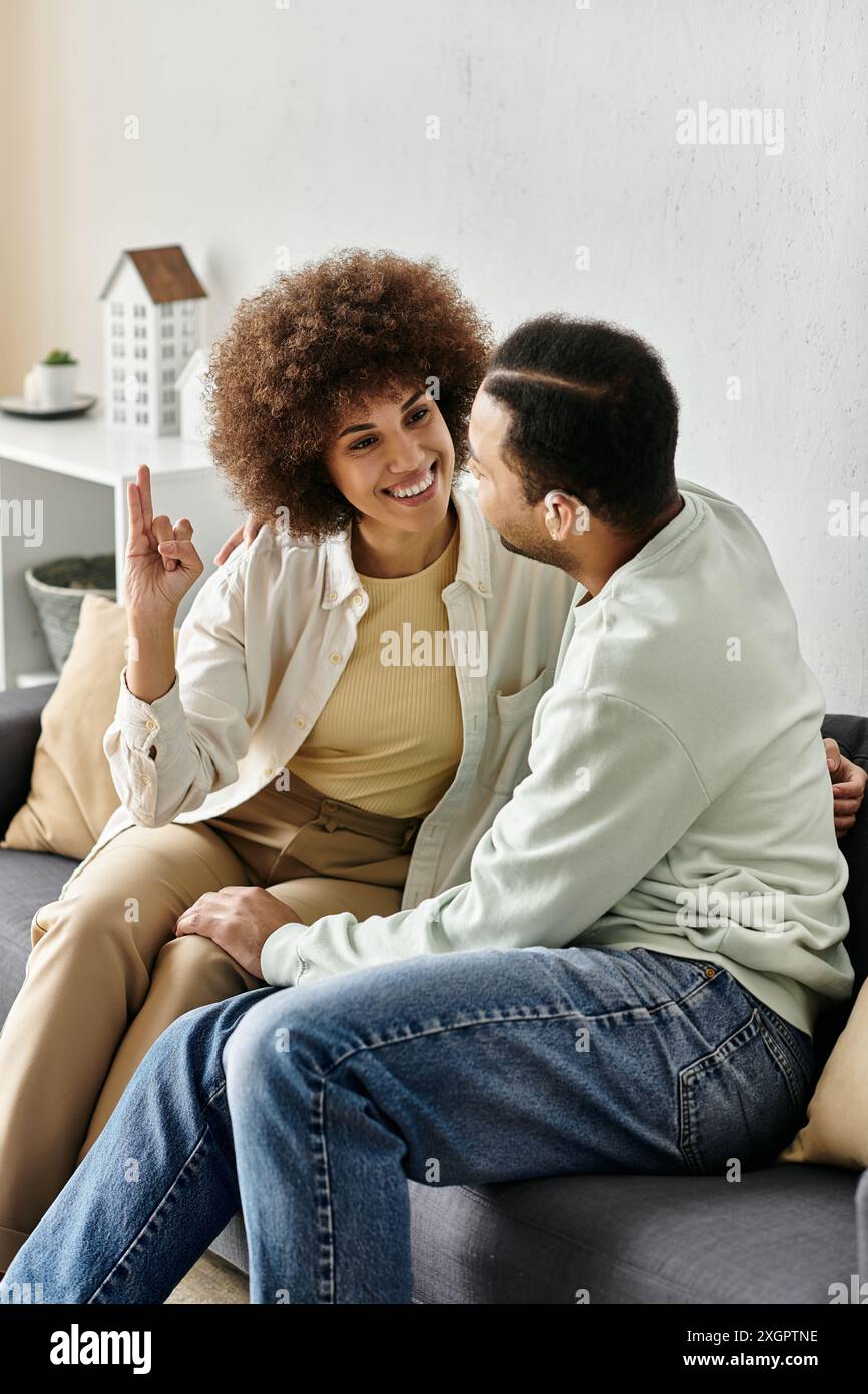 Un'affettuosa coppia afroamericana comunica attraverso il linguaggio dei segni mentre si rilassa a casa. Foto Stock