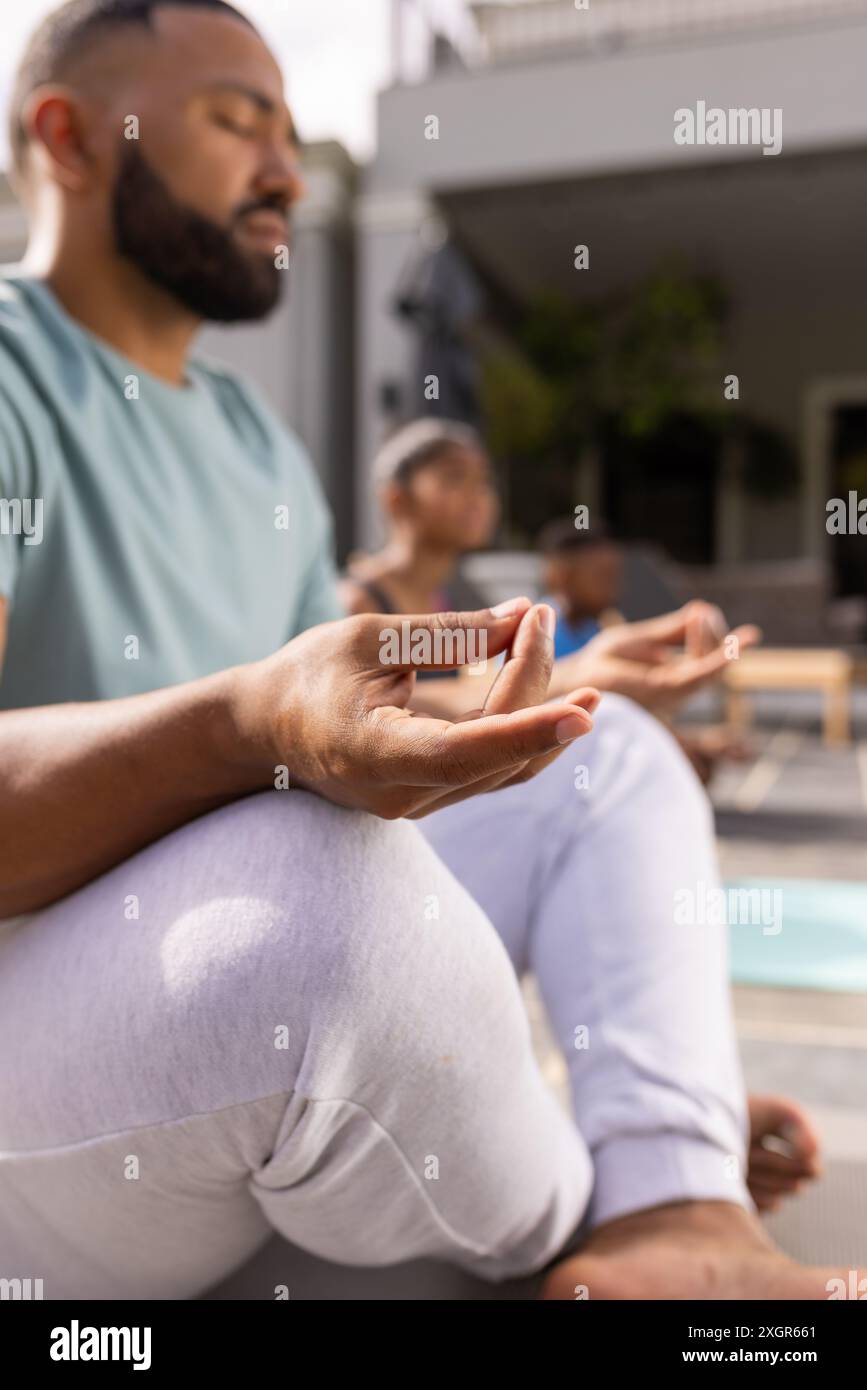 Il giovane uomo birazziale medita all'aperto, con spazio di copia. La serenità scorre mentre pratica yoga in un tranquillo giardino di casa. Foto Stock