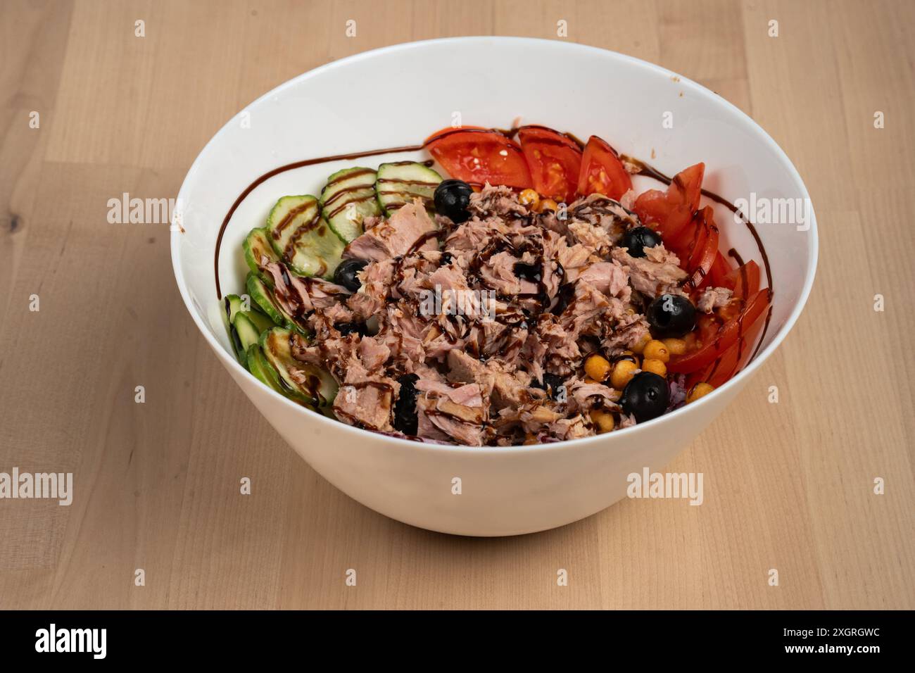 Vista dall'alto di un recipiente per insalate fresco con pollo croccante, cetrioli, pomodori e cipolle rosse su un tavolo di legno Foto Stock