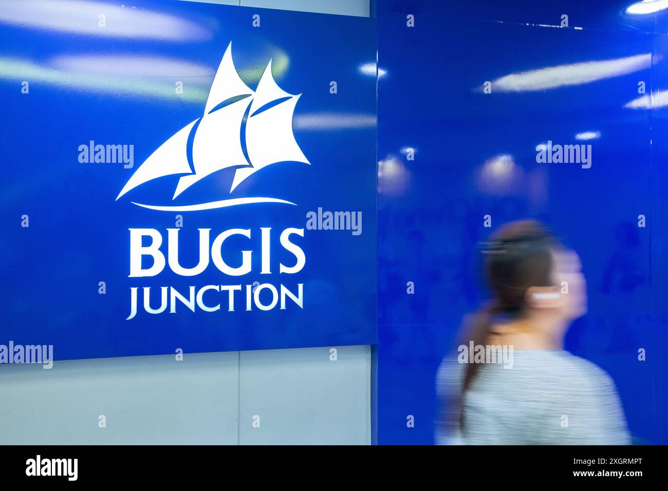 Logo Bugis Junction per una passerella femminile in slow motion, schema di colore blu. Il centro commerciale è gestito da CapitaLand Group. Singapore. Foto Stock