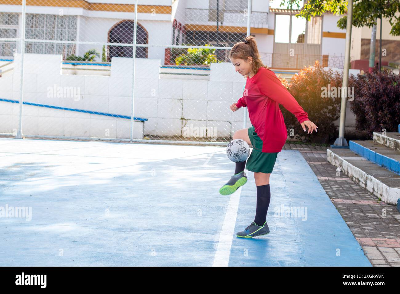 Concetti: Sport femminili e attività ricreative all'aperto. giovane donna che gioca a calcio in un ambiente urbano. esercizio fisico e stile di vita attivo Foto Stock