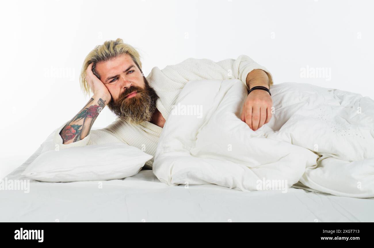 Buon giorno. Un uomo da sogno a letto, svegliarsi rilassati e godersi un fine settimana tranquillo a casa. Bell'uomo barbuto sdraiato a letto, si sveglia la mattina. Attraente Foto Stock