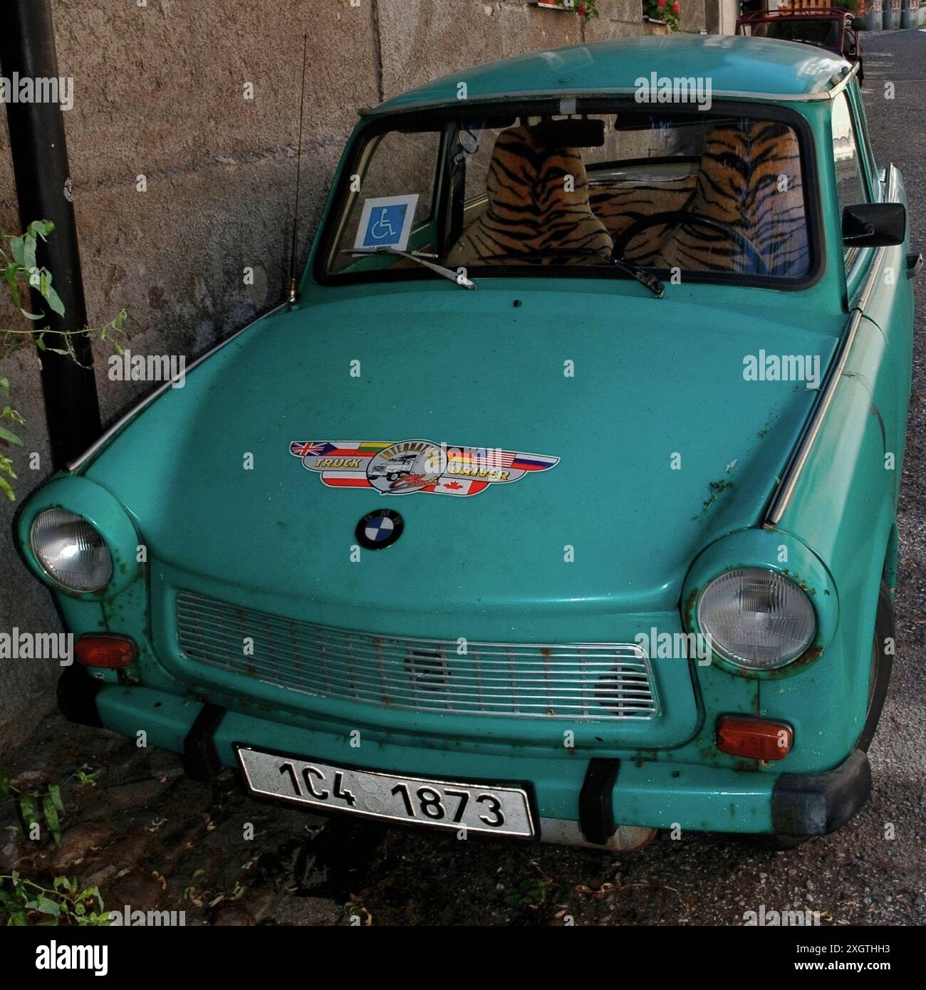 Trabant: Un'auto che divenne famosa con la caduta del muro di Berlino nel 1989, quando migliaia di persone furono viste sugli schermi televisivi di tutto il mondo in coda per attraversare il confine dalla Germania Est alla Germania Ovest. Questa Trabant verde arrugginente con coprisedili in finta pelle di tigre fu parcheggiata a Tábor, Boemia meridionale, Cechia, nel 2006. È dotato di un logo BMW falso e di un adesivo "International Truck driver" sul cofano o sul cofano e di un permesso di parcheggio per disabili nel parabrezza. Lanciata nella Germania Est nel 1957, la Trabant è talvolta definita “la peggiore auto di sempre” e simbolo del fallimento del comunismo. Foto Stock