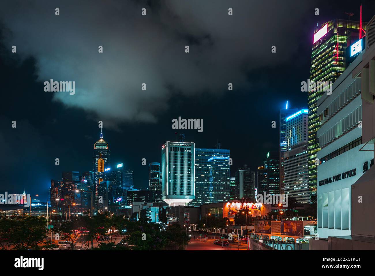 Hong Kong - 19 luglio 2017: Paesaggio urbano notturno del quartiere centrale, skyline urbano con grattacieli illuminati sotto il cielo nuvoloso Foto Stock