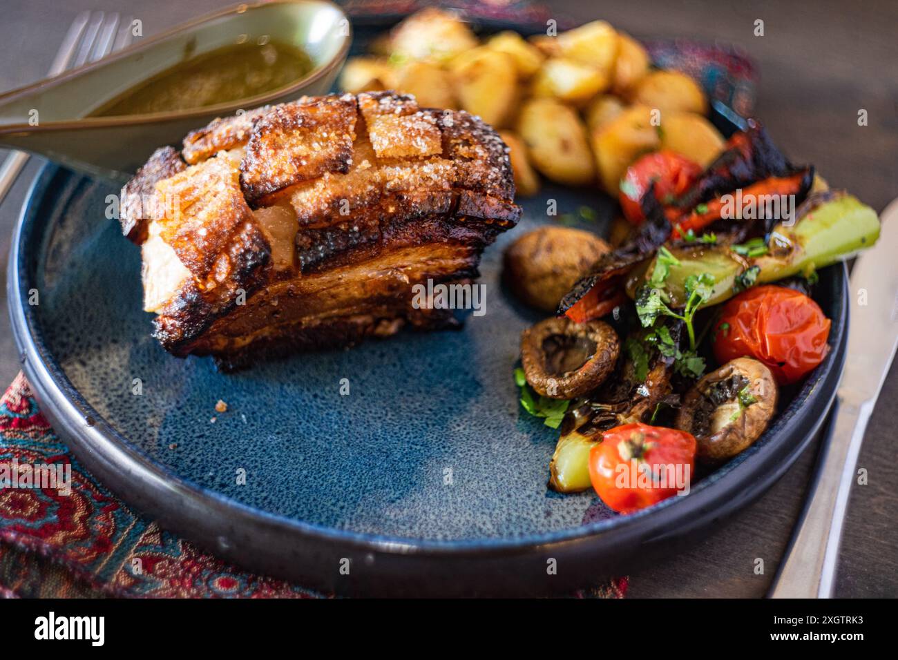 Costolette di maiale croccanti al forno, abbondantemente condite con una salsa al miele, accompagnate da un'insalata di verdure grigliate colorate su un piatto di ceramica Foto Stock