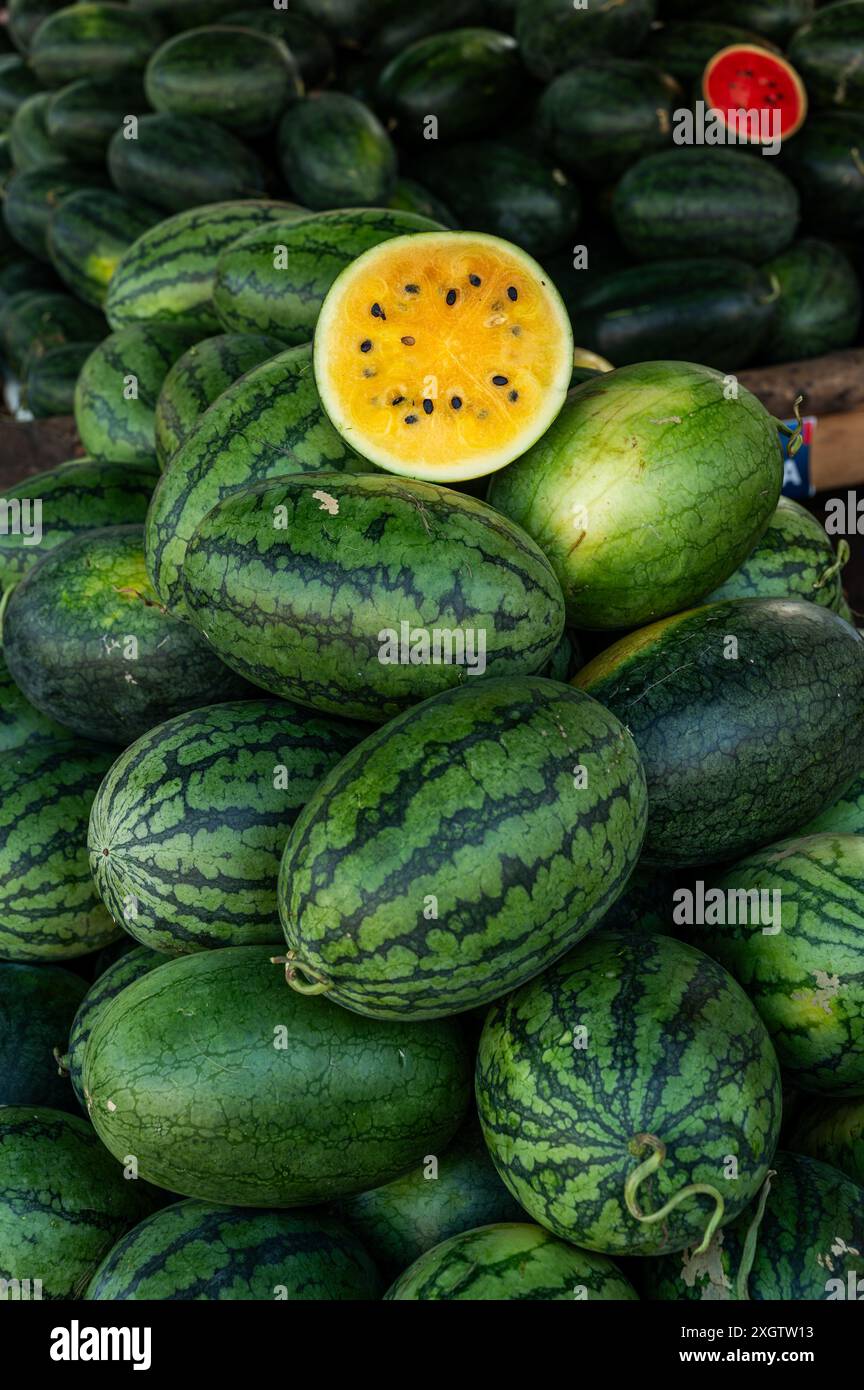 Un vivace spettacolo di angurie gialle, con un taglio aperto per mostrare succosa carne gialla, in un tradizionale mercato vietnamita di strada. Foto Stock