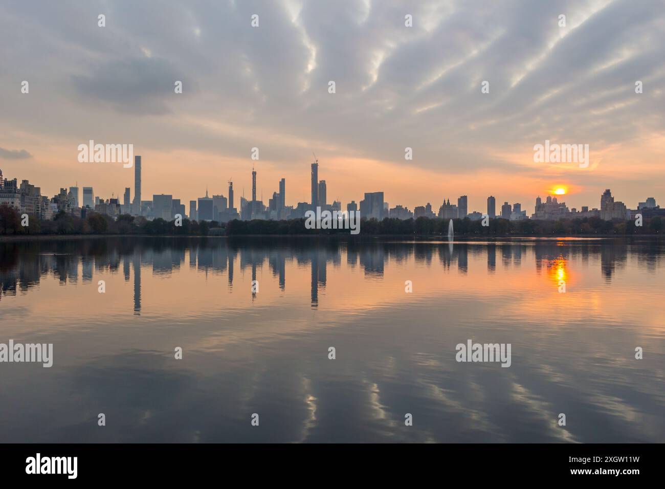 Skyline di Manhattan e riflessione sul lago a Central Park al tramonto. New York Foto Stock
