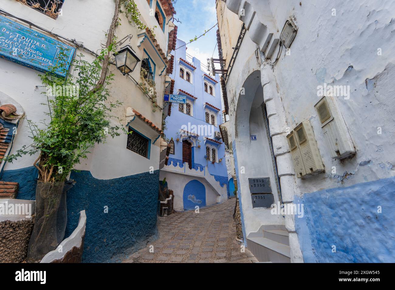 Chefchaouen, Marocco - 25 marzo 2024: Un pittoresco vicolo con edifici blu e bianchi. La città è conosciuta per le sue mura dipinte di blu e l'affascinante labirinto Foto Stock