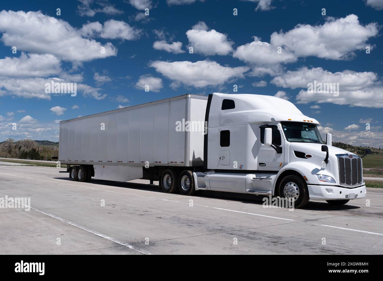 Un grande carro di perforazione bianco a 18 ruote sotto un cielo blu con nuvole accanto all'autostrada parcheggiata Foto Stock