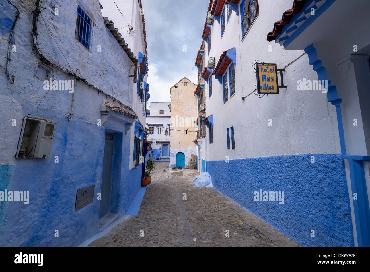 Un vecchio cartello dell'hotel pende sul muro del vicolo stretto. Marocco. Le case nelle tonalità del blu e del bianco sono sognanti e affascinanti. Chefchaouen. Foto Stock