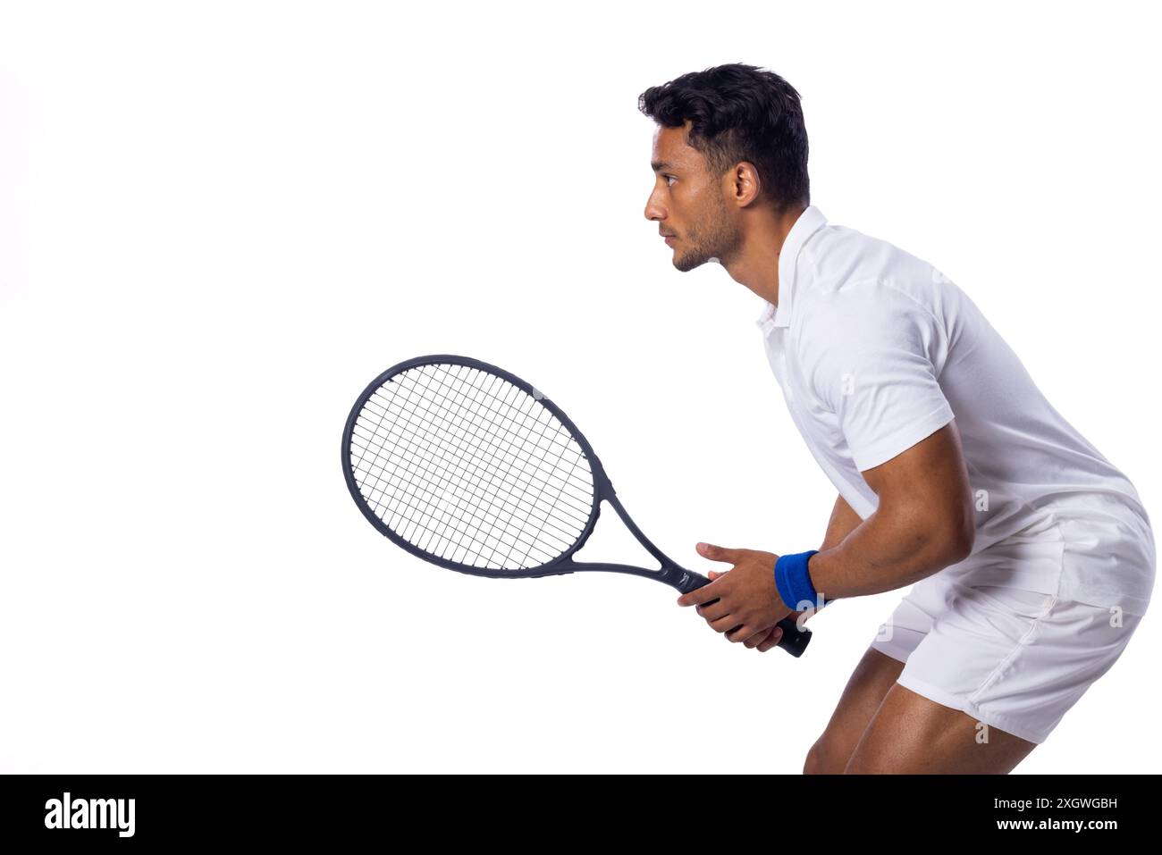 Uomo birazziale concentrato che gioca a tennis al chiuso su uno sfondo bianco, con spazio di copia. La sua posizione e concentrazione mostrano l'intensità dello sport. Foto Stock