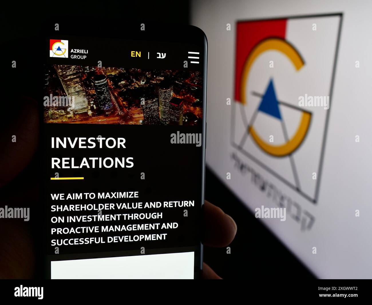 Persona che detiene lo smartphone con la pagina Web della società immobiliare israeliana Azrieli Group Ltd. Davanti al logo. Messa a fuoco al centro del display del telefono. Foto Stock