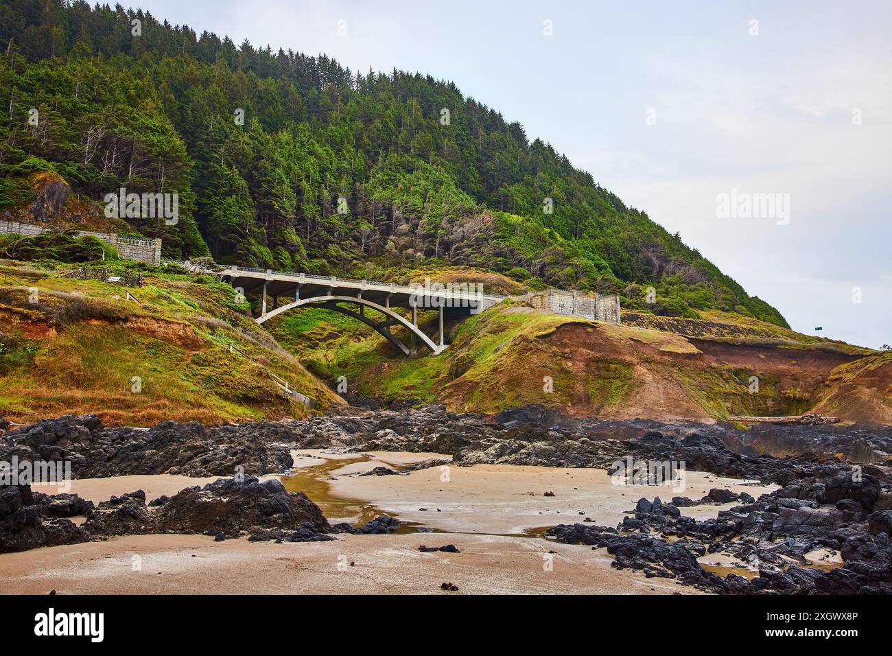 Ponte costiero tra colline lussureggianti dal punto di vista della spiaggia Foto Stock