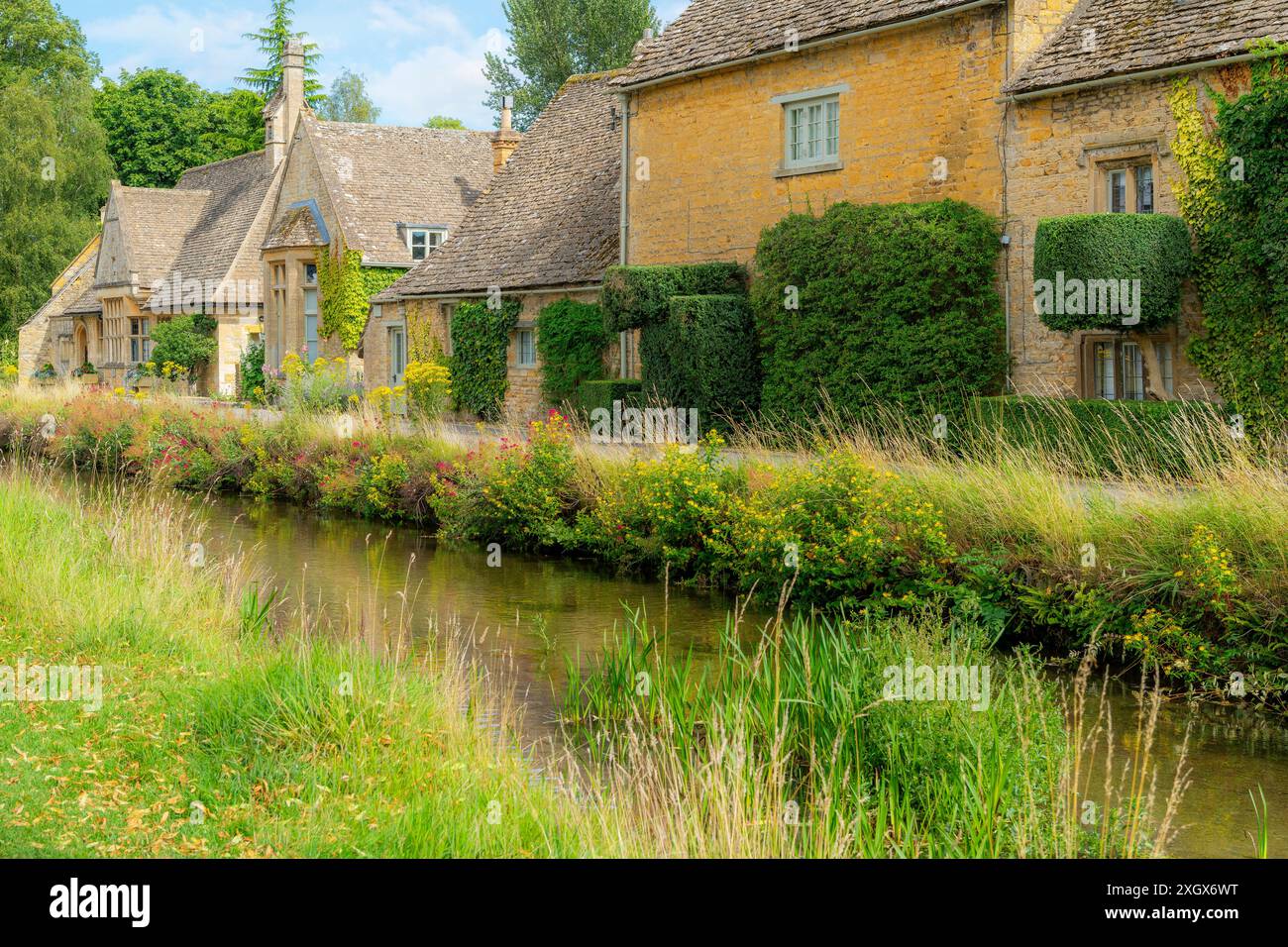 Cottage in pietra lungo il fiume Eye presso il pittoresco villaggio inglese di Lower Slaughter, nel distretto di Cotswold nel Gloucestershire, in Inghilterra. Foto Stock