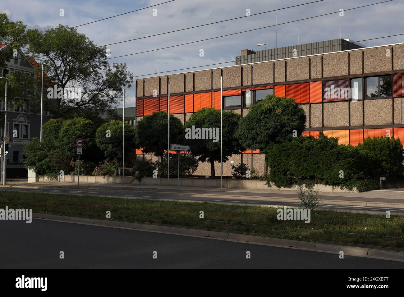 Edificio in stile brutalista a Oberricklingen, Hannover, Germania, con persiane arancioni e alberi davanti al sole pomeridiano Foto Stock