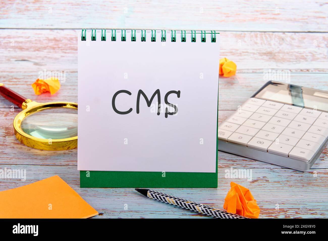 Acronimo CMS (Content Management System) in un notebook verticale in composizione con forniture per ufficio Foto Stock