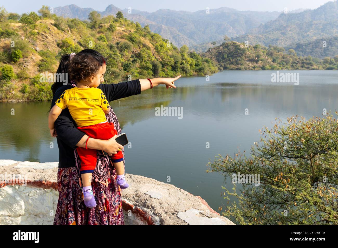 madre mostra un paesaggio incontaminato al figlio di giorno da un angolo piatto Foto Stock