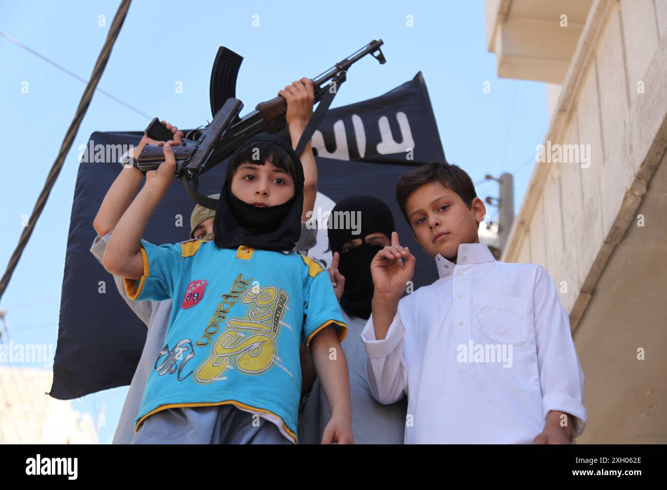 I bambini trasportano armi durante una dimostrazione a sostegno di al-Nusra e Isis ad Aleppo. An-Nusra è un'organizzazione collegata ad al-Qaeda Foto Stock