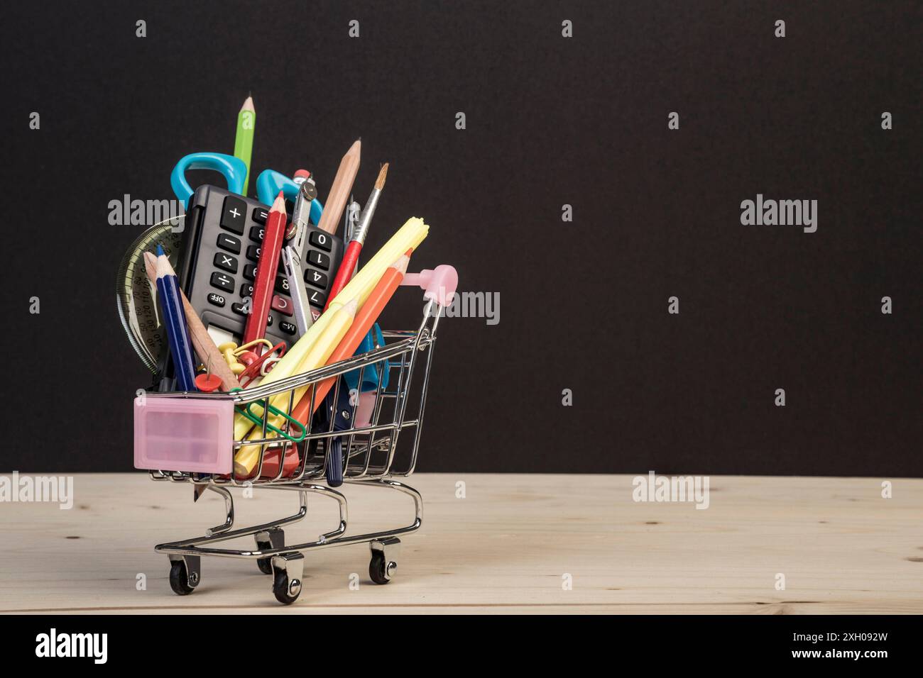 modello back to school con più articoli di cancelleria nel carrello con spazio per le copie su sfondo nero. informazioni di base sul concetto didattico con spazio di copia. Foto Stock