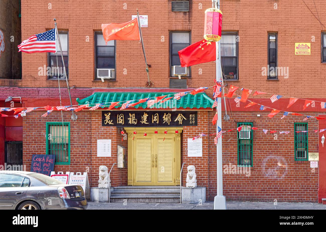 NYC Chinatown: Bandiere e simboli cinesi circondano la porta color oro degli ex uffici della Fukien Benevolent Association of America. Foto Stock